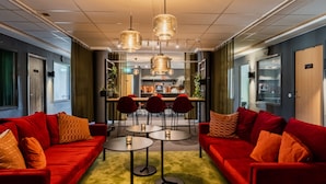 A modern hotel lobby with red sofas, round tables, and pendant lighting. - Hotell Fridhemsgatan (Mora)