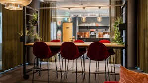 A modern dining area with a long table, red chairs, and pendant lighting. - Hotell Fridhemsgatan (Mora)
