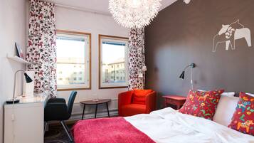 A hotel room with a bed, a desk, a chair, a small table, and a window.