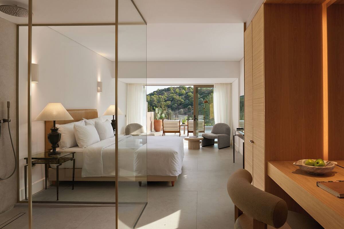 Ein modernes Hotelzimmer mit einem großen Bett, einem Schreibtisch und Blick auf eine Berglandschaft.