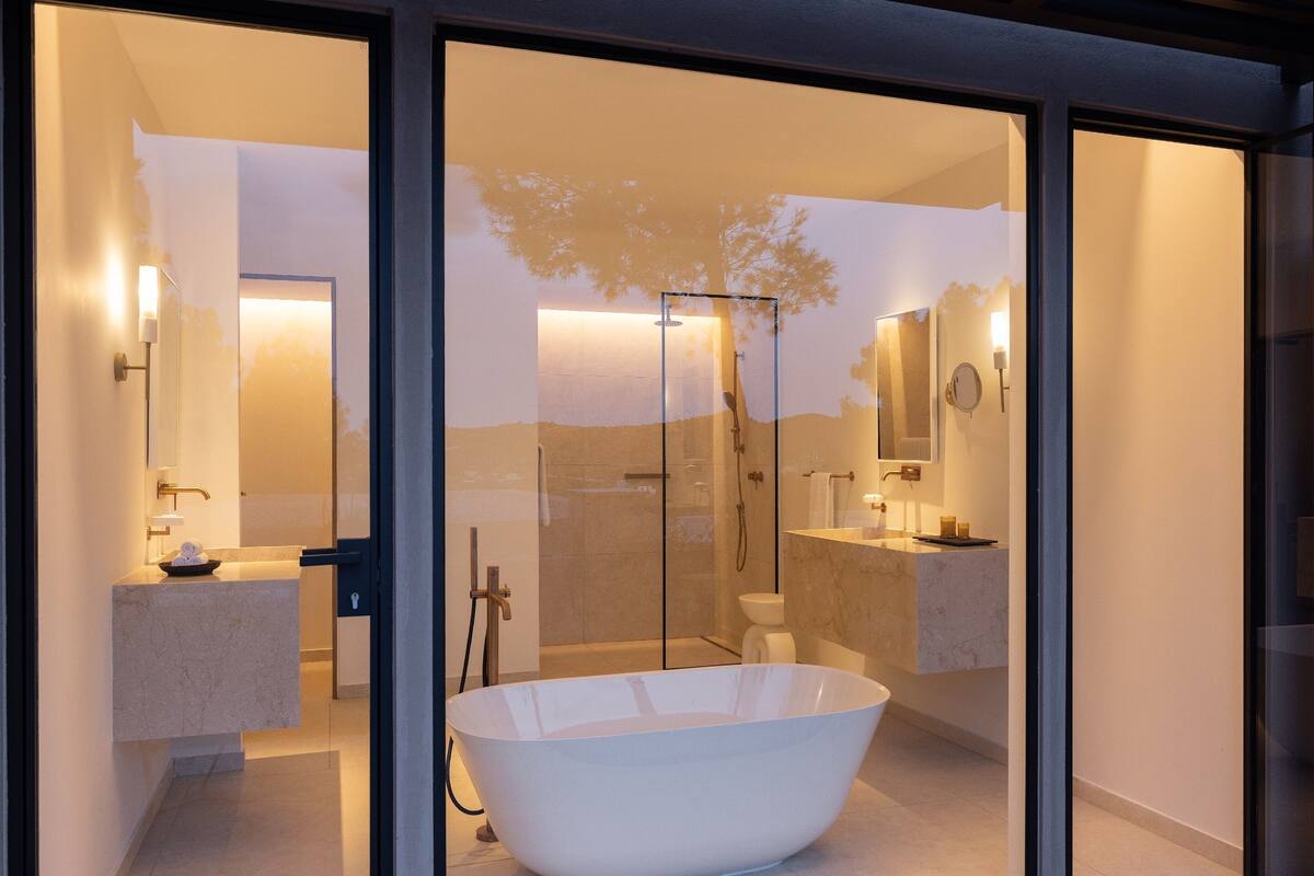 Ein modernes Badezimmer mit freistehender Badewanne, Duschkabine aus Glas und einem großen Spiegel.