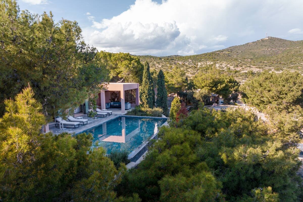 Ein Pool mit Liegestühlen, einer überdachten Sitzgelegenheit und einem Bergpanorama.