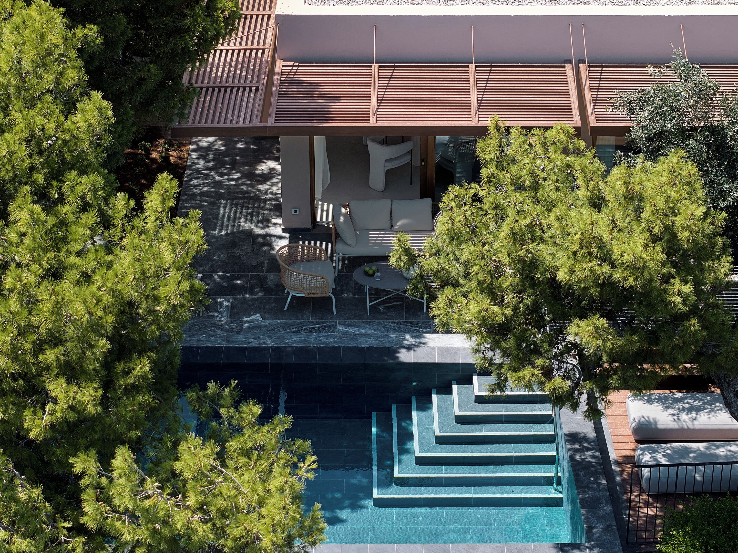 An aerial view of a modern house with a swimming pool, outdoor furniture, and lush greenery.