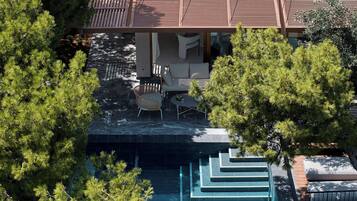 An aerial view of a modern house with a swimming pool, outdoor furniture, and lush greenery.