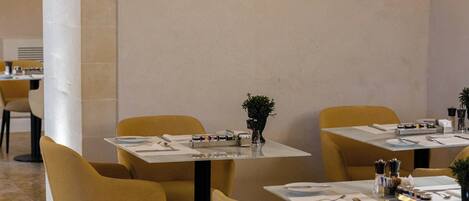 A restaurant with tables and chairs, a stone wall, and a tiled floor.