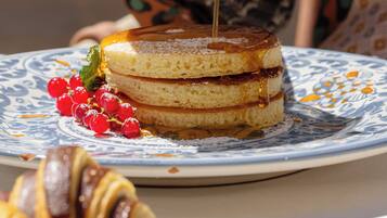 A person pouring syrup over a layered cake on a plate.
