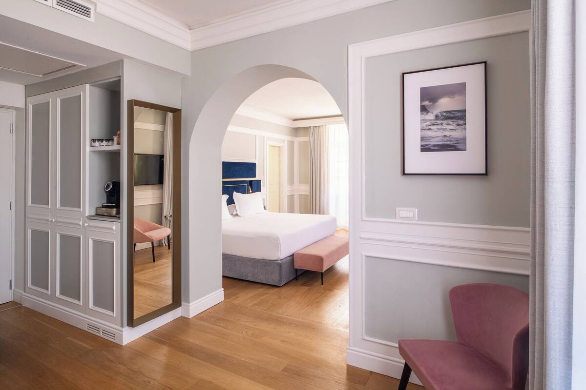 Une chambre d’hôtel avec un lit, une chaise, une armoire et un tableau encadré au mur.