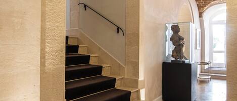 A grand staircase with stone steps and black carpeted landings, leading to an upper level.