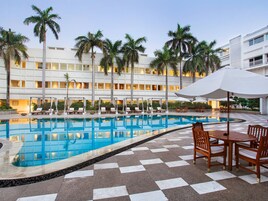 Una piscina al aire libre, sombrillas, sillones reclinables de piscina
