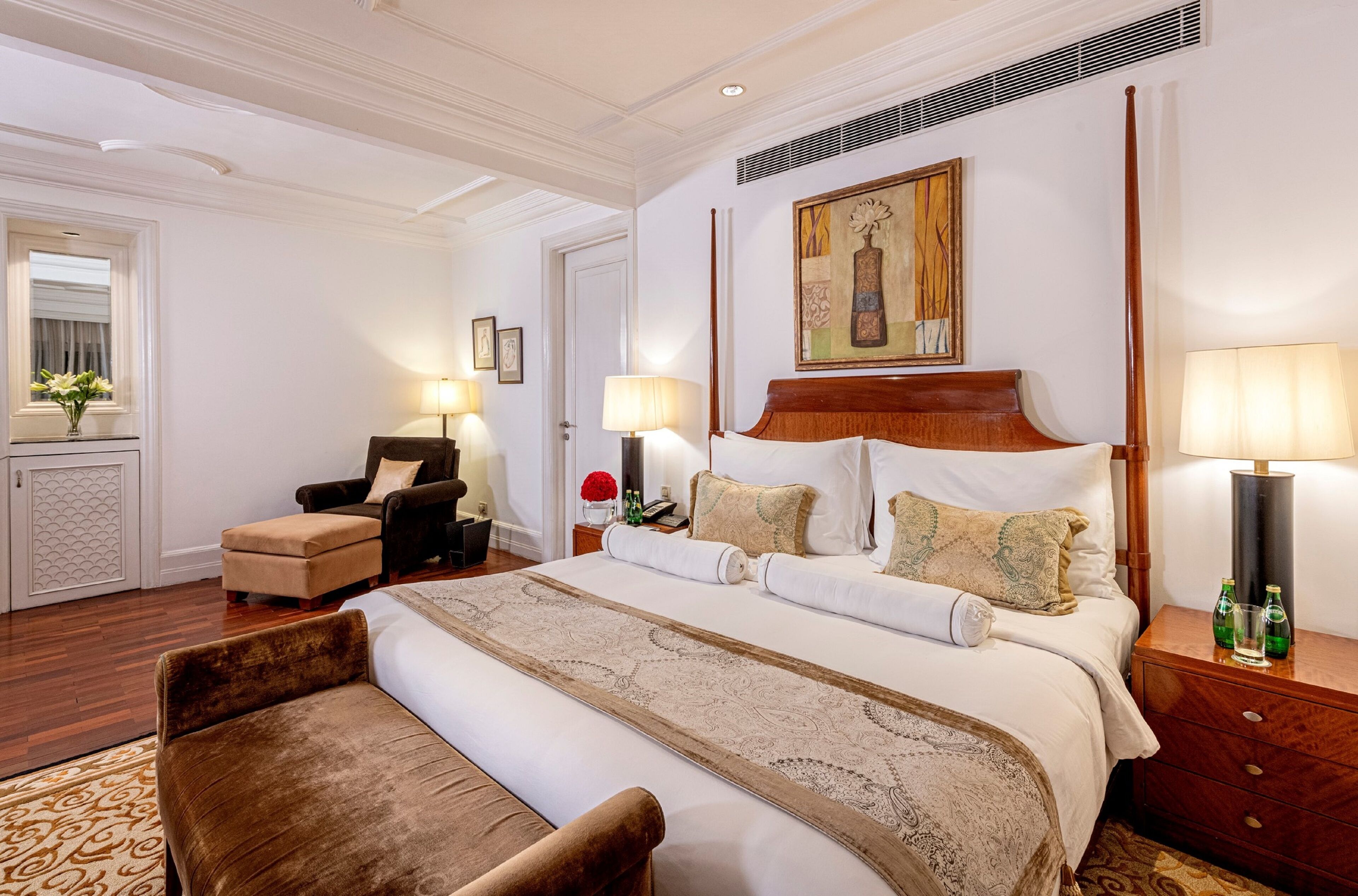 Une chambre d’hôtel avec un grand lit, une chaise, une table de chevet et un tableau au mur.