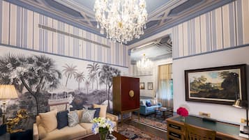 Un salon luxueux avec un papier peint à rayures, un lustre, un canapé, une table basse et un tableau.
