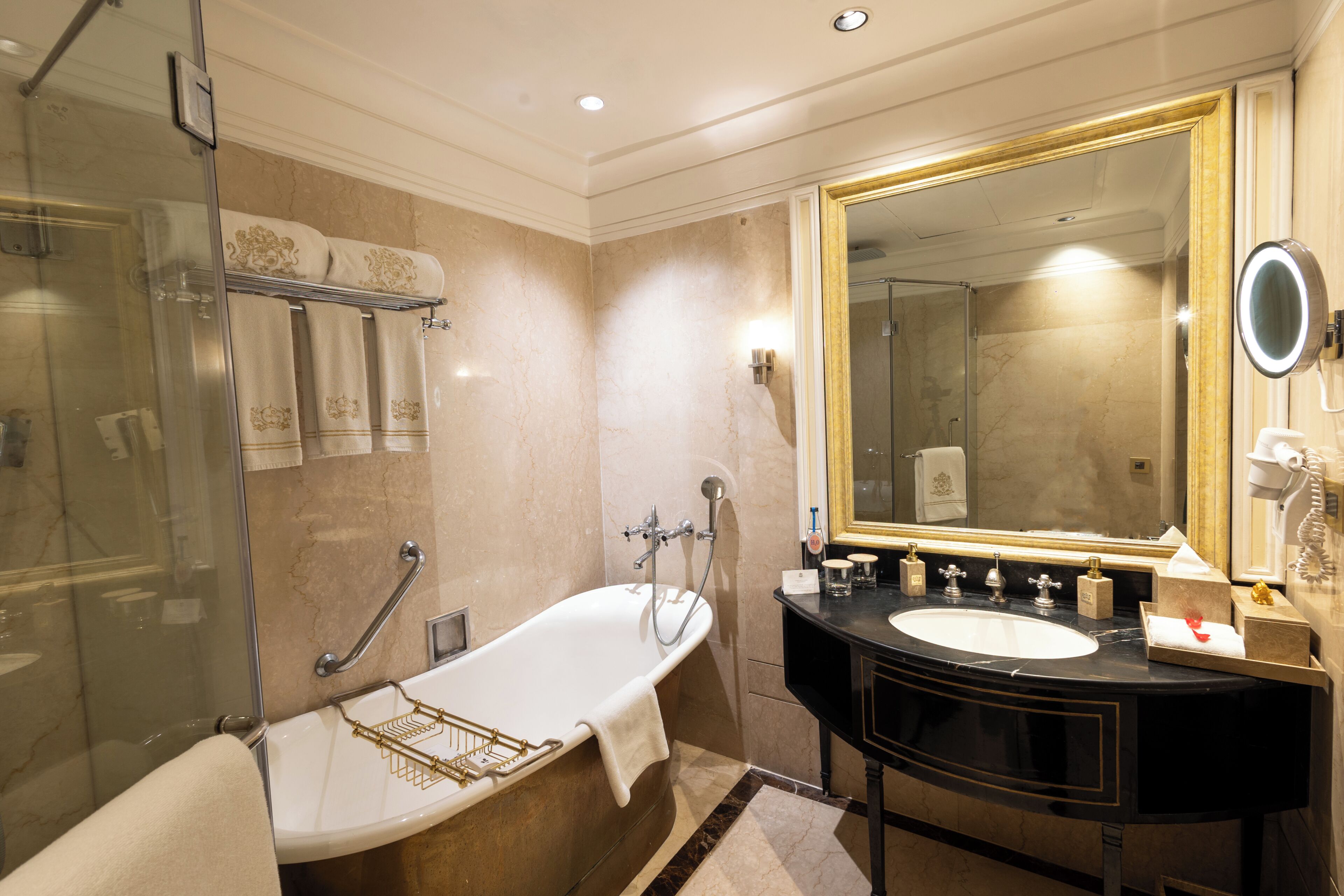 A bathroom with a bathtub, a large mirror, a vanity with a sink, and a shower area.