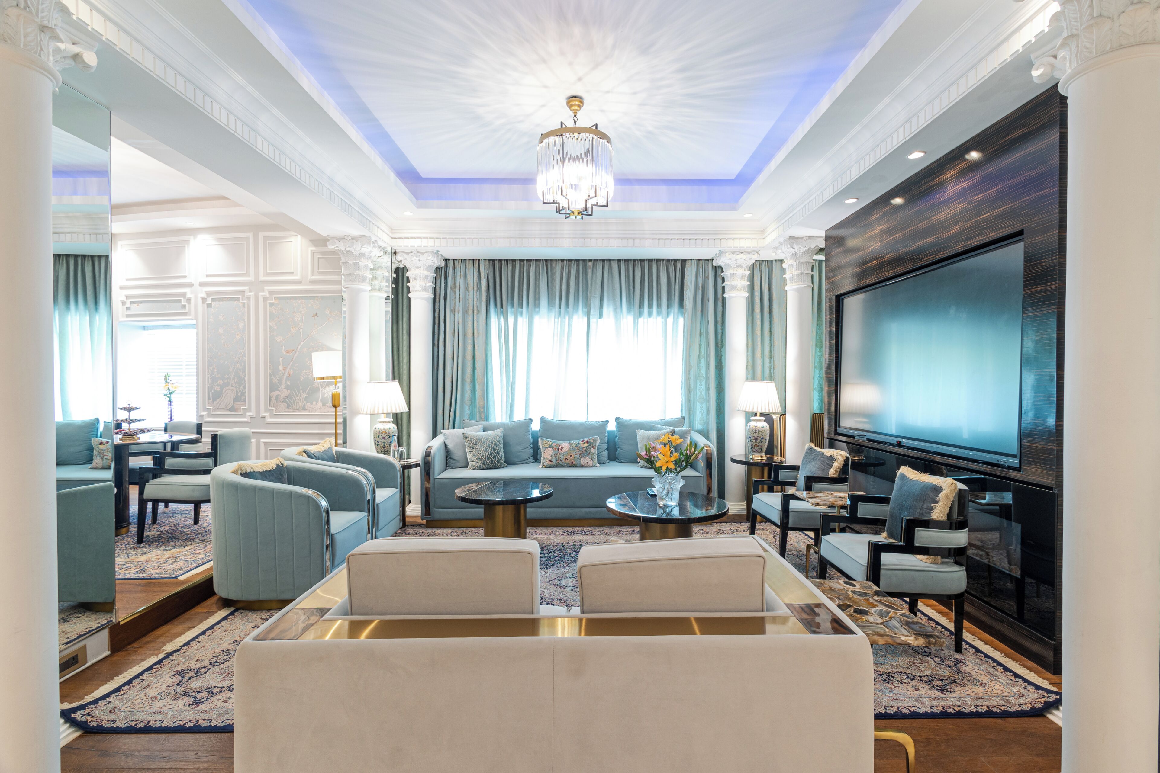 A spacious living room with a large flat-screen TV, comfortable seating, and a decorative chandelier.