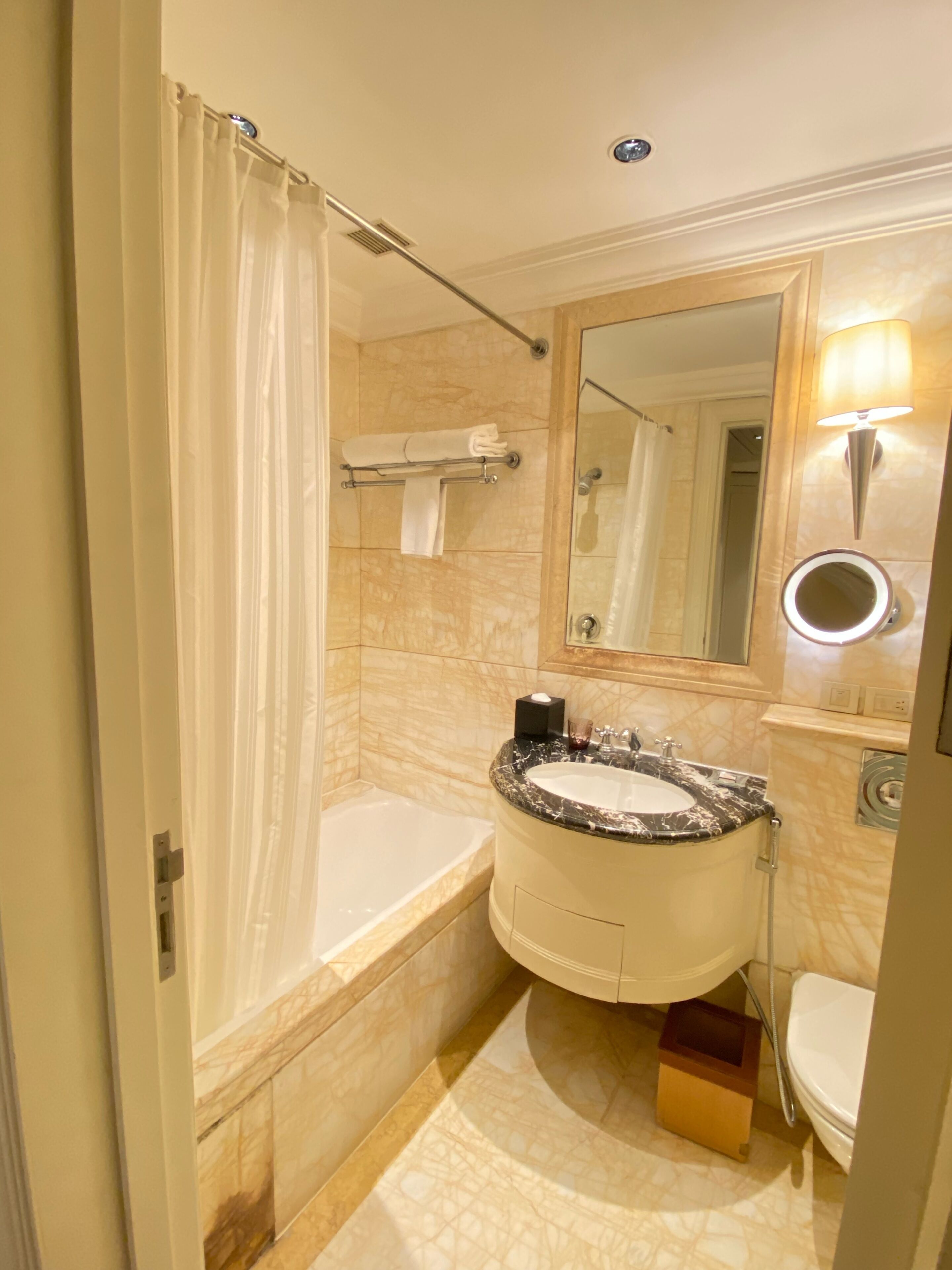 Un baño con bañera, lavamanos, inodoro, espejo y cortina de ducha.