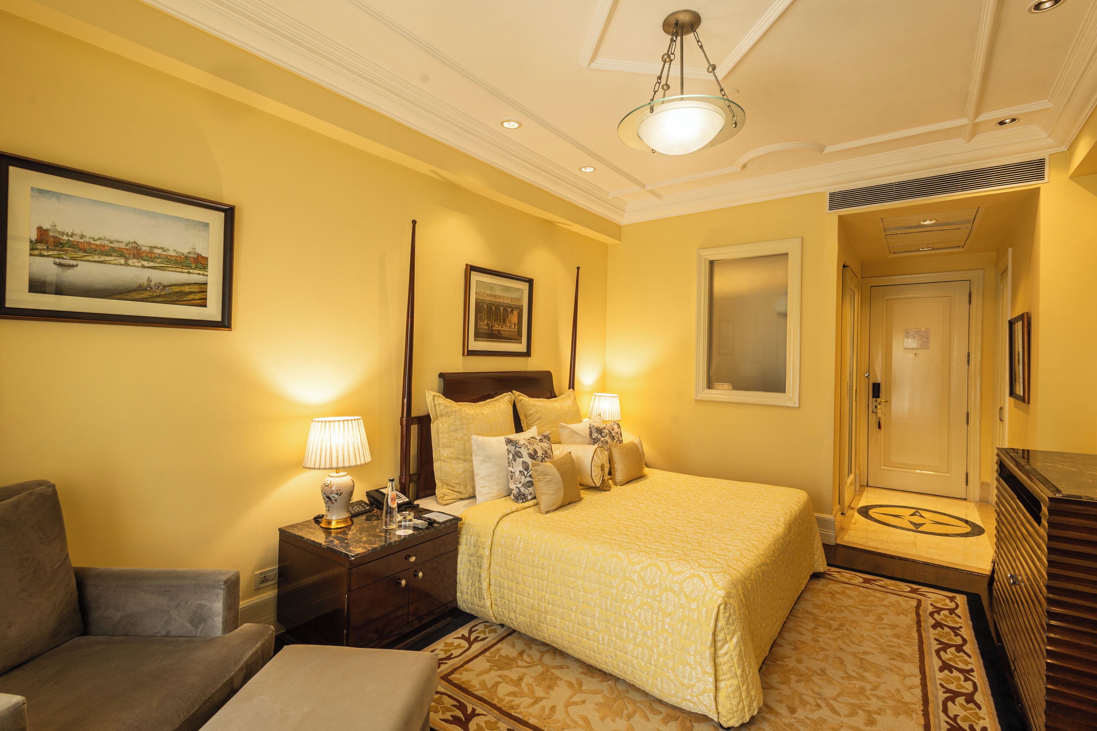 A hotel room with a bed, bedside tables, a lamp, a painting on the wall, and a door.