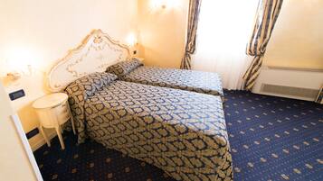 A bedroom with two beds, a bedside table, and a window with curtains.