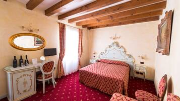 A hotel room with a wooden ceiling, a bed with a patterned bedspread, a desk with a mirror, and a dresser.