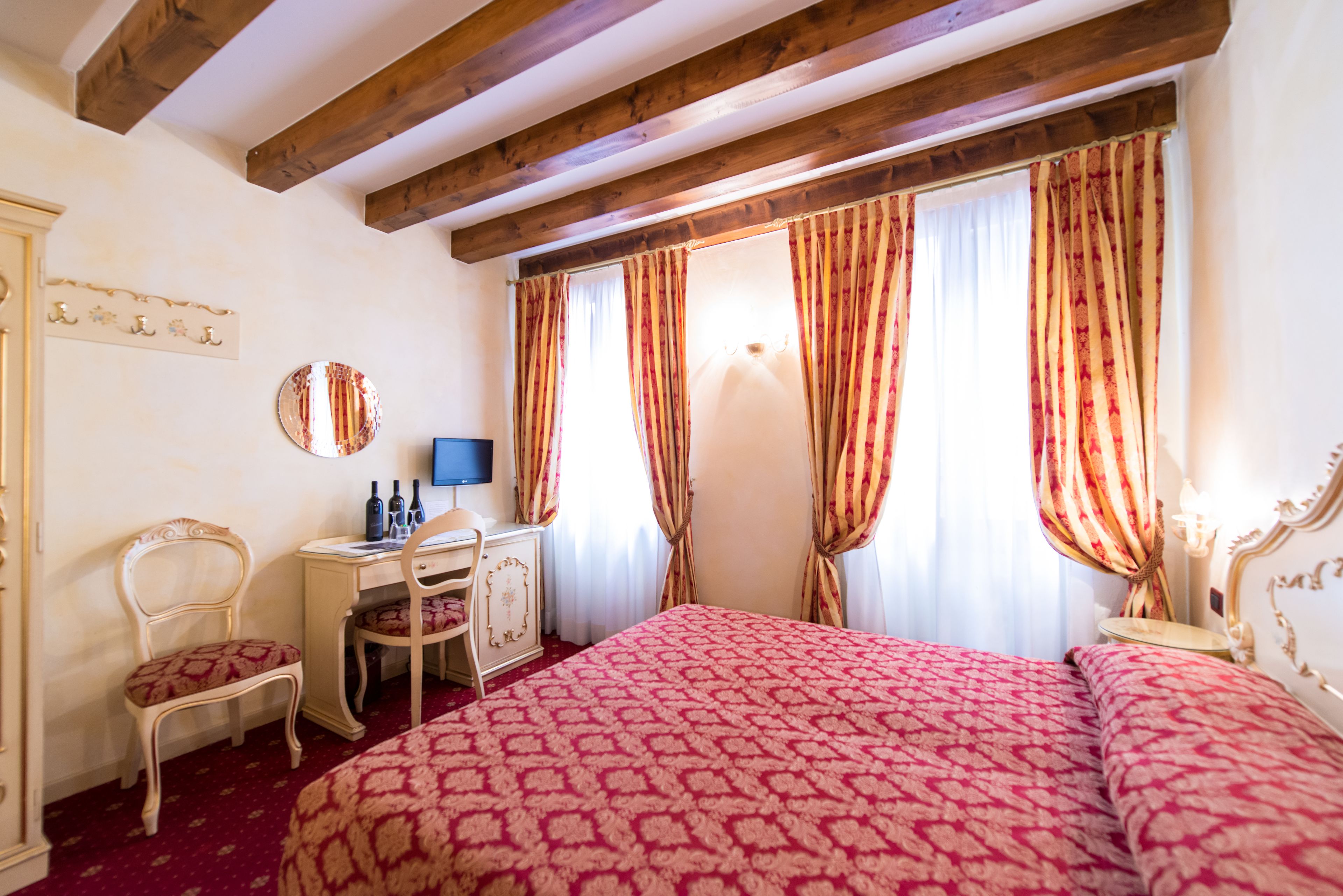 Une chambre d’hôtel avec un grand lit, un bureau avec une chaise, une commode et un miroir.