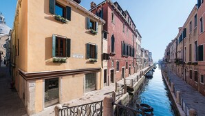 A narrow canal flanked by historic buildings with balconies and shutters. - Locanda Ca' Zose (Venice)