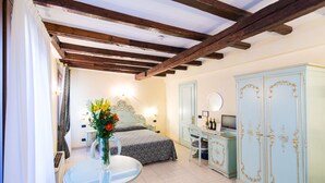 A bedroom with a bed, a desk, a chair, a wardrobe, and a small table with a vase of flowers. - Locanda Ca' Zose (Venice)