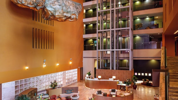 A spacious lobby with a central seating area, a reception desk, and a staircase leading to upper floors. - Hotel Melia Bilbao (Bilbao)
