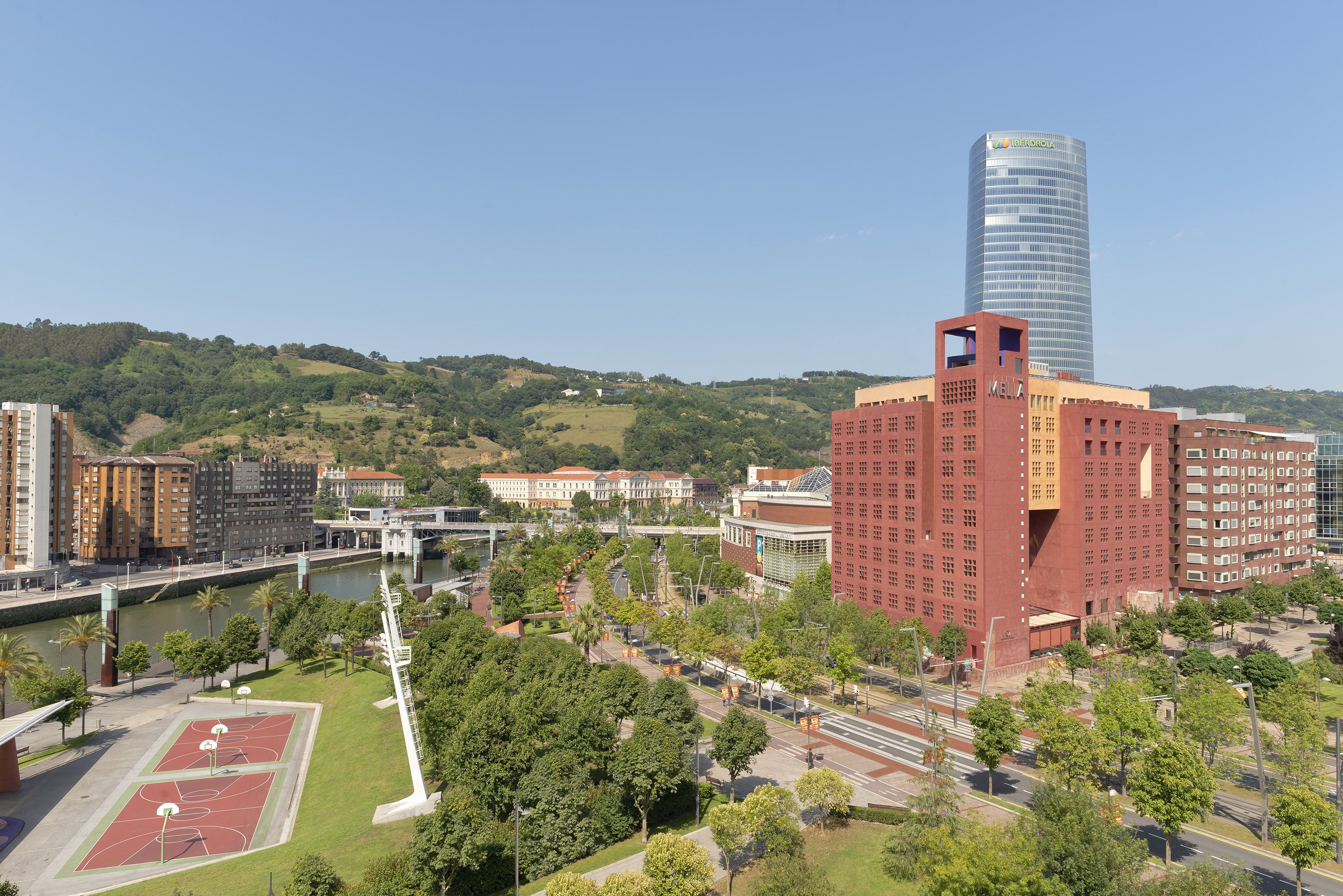 A cityscape with a prominent red building, a modern skyscraper, and a river.
