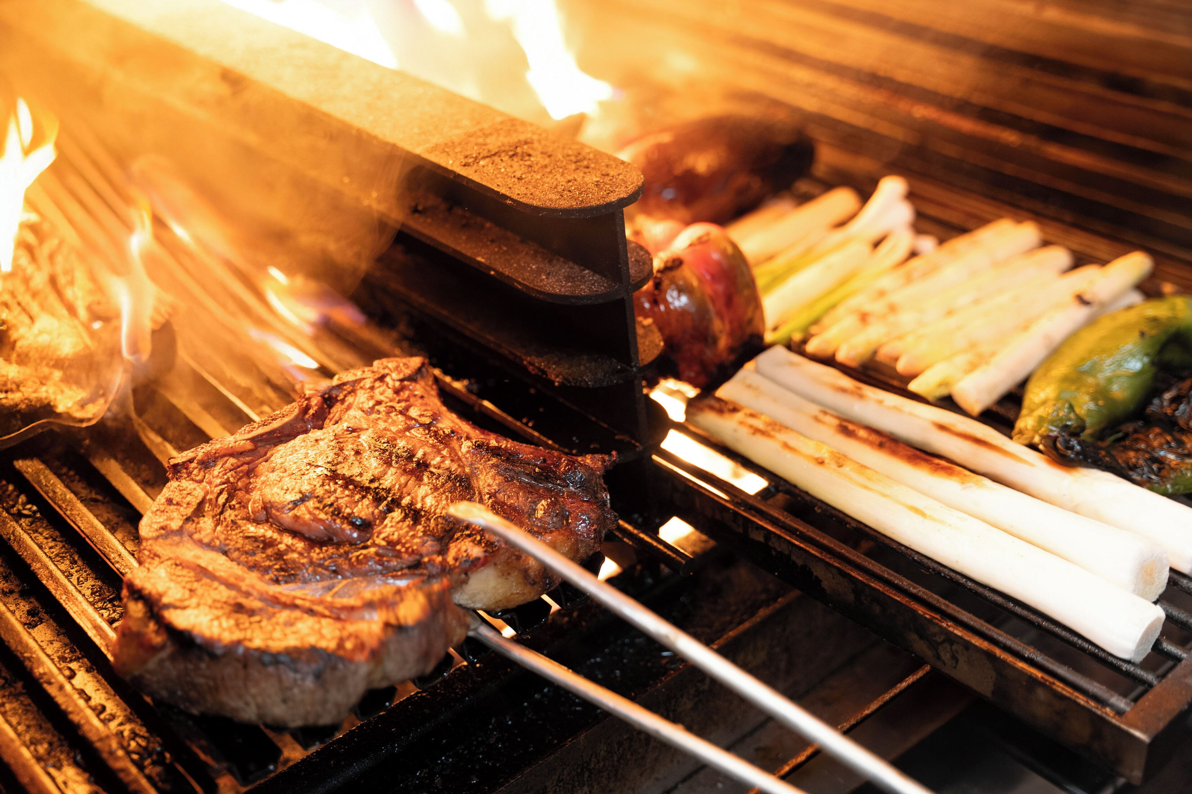 A grill with various meats and vegetables being cooked.