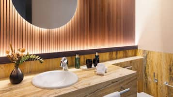 Une salle de bain moderne avec un grand lavabo ovale, un miroir orné d’un motif en bois et un plan de toilette en marbre.