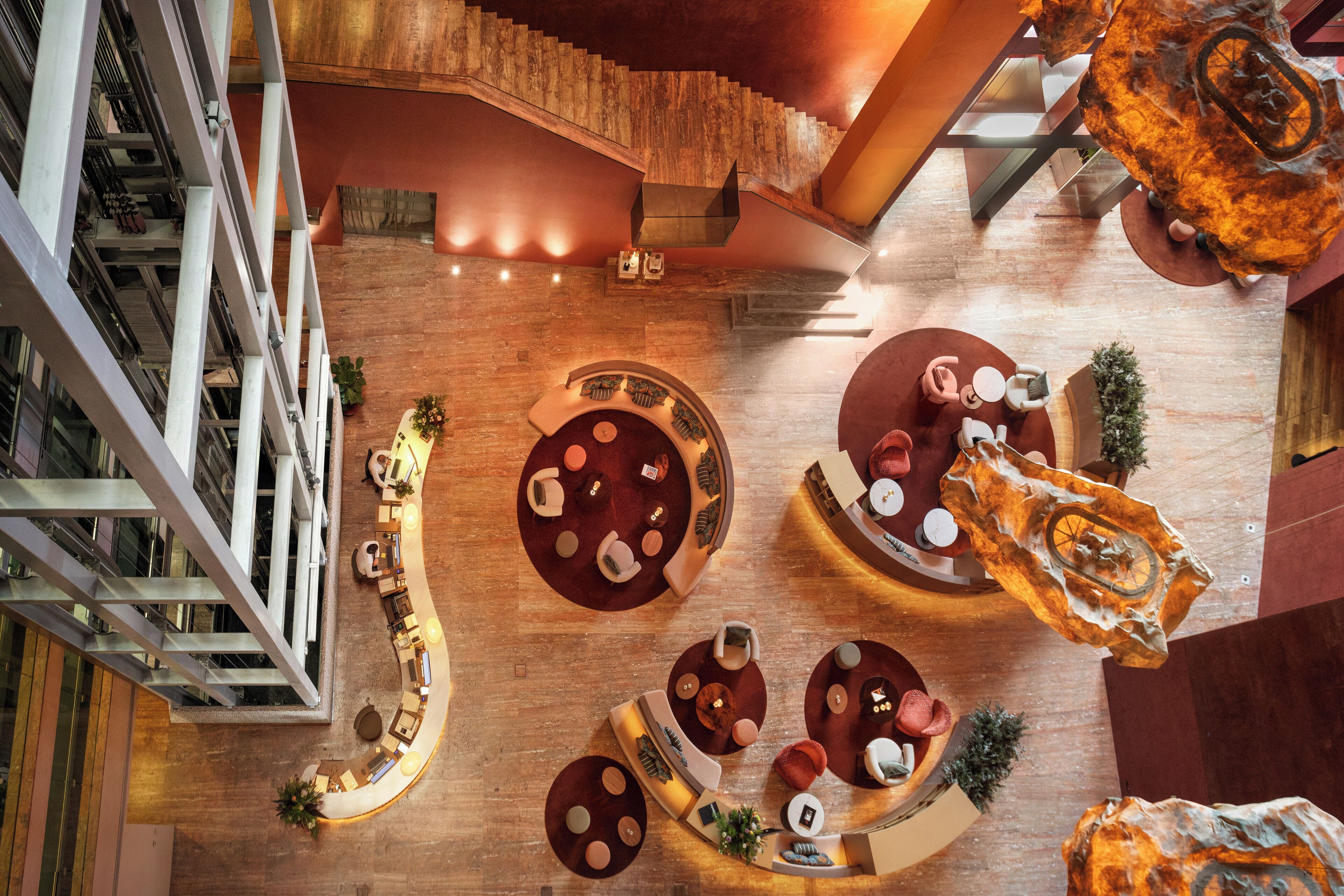 A spacious atrium with a curved seating area, a staircase, and a large, unique sculpture.
