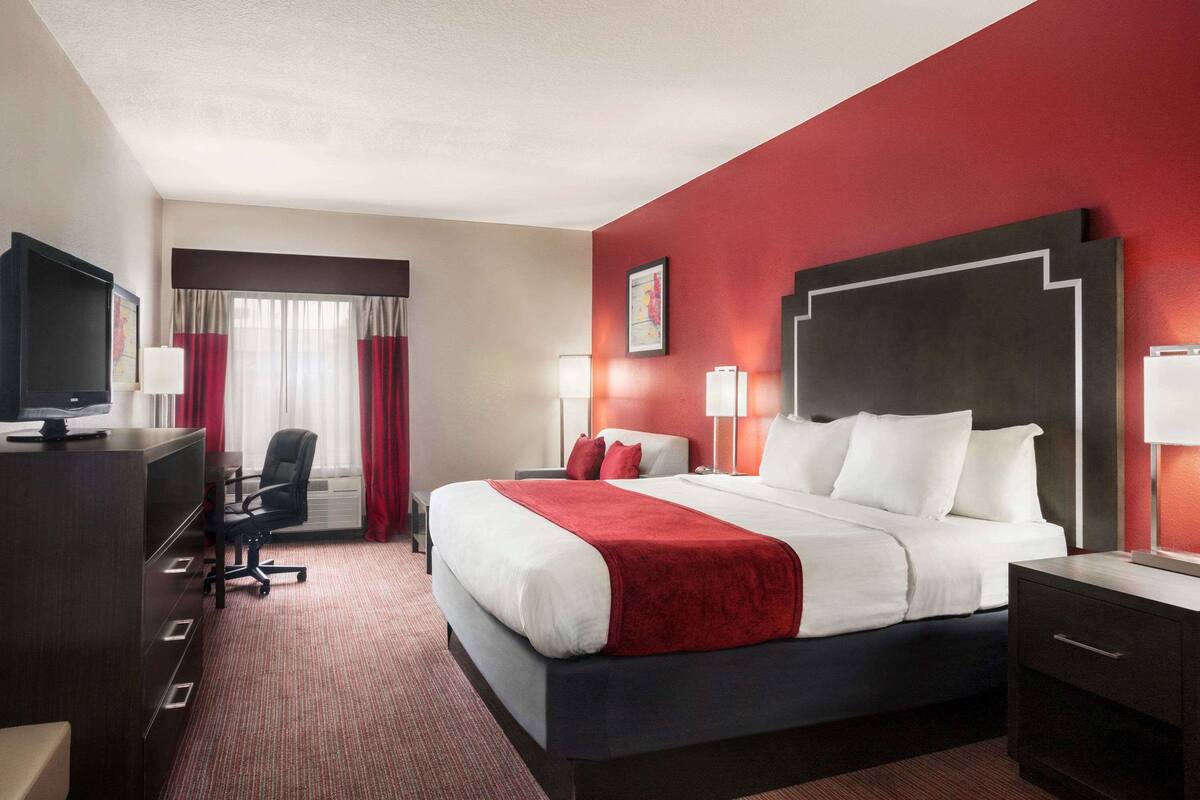 Une chambre d’hôtel avec un grand lit, un bureau, une chaise et un téléviseur.