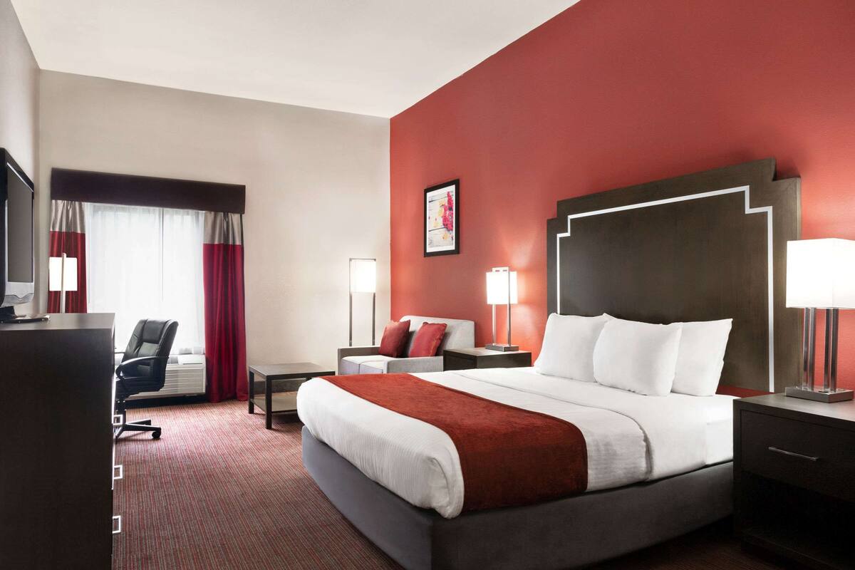 Une chambre d’hôtel avec un grand lit, un bureau, une chaise et un téléviseur.