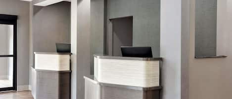 A reception area with two reception desks, a glass door entrance, and a modern interior design.