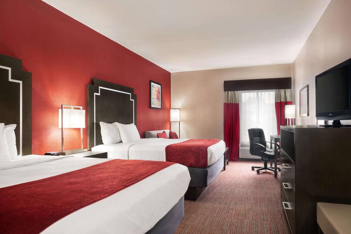 Une chambre d’hôtel avec deux lits, un bureau, une télévision et une chaise.