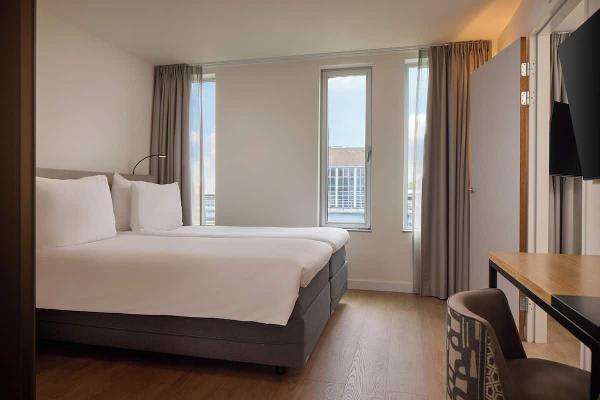 Una habitación de hotel con una cama, un escritorio y un televisor.