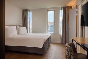 Ein Hotelzimmer mit einem Bett, einem Schreibtisch und einem Fernseher.