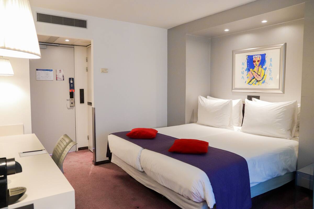 Una habitación de hotel con una cama, un escritorio y una silla.
