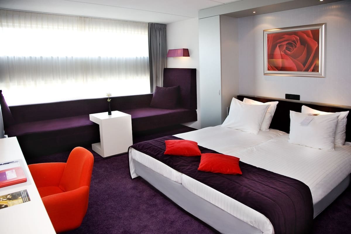 Una habitación de hotel con cama, sofá, una mesita y una silla.