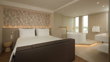 Una habitación de hotel moderna con una cama grande, un baño independiente con bañera y vistas a la ciudad.