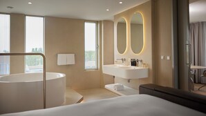 Une salle de bain d’hôtel moderne, dotée d’une baignoire, d’un lavabo et d’un grand miroir.