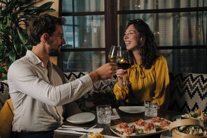 Un coin repas avec une table dressée pour deux personnes, comprenant une assiette de nourriture et un verre de vin.