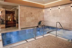 A modern spa area with a hot tub, a wooden vanity, and a decorative wall.