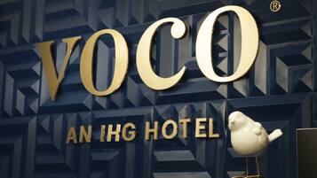 A hotel sign with the name "Voco An Igh Hotel" and a bird decoration.