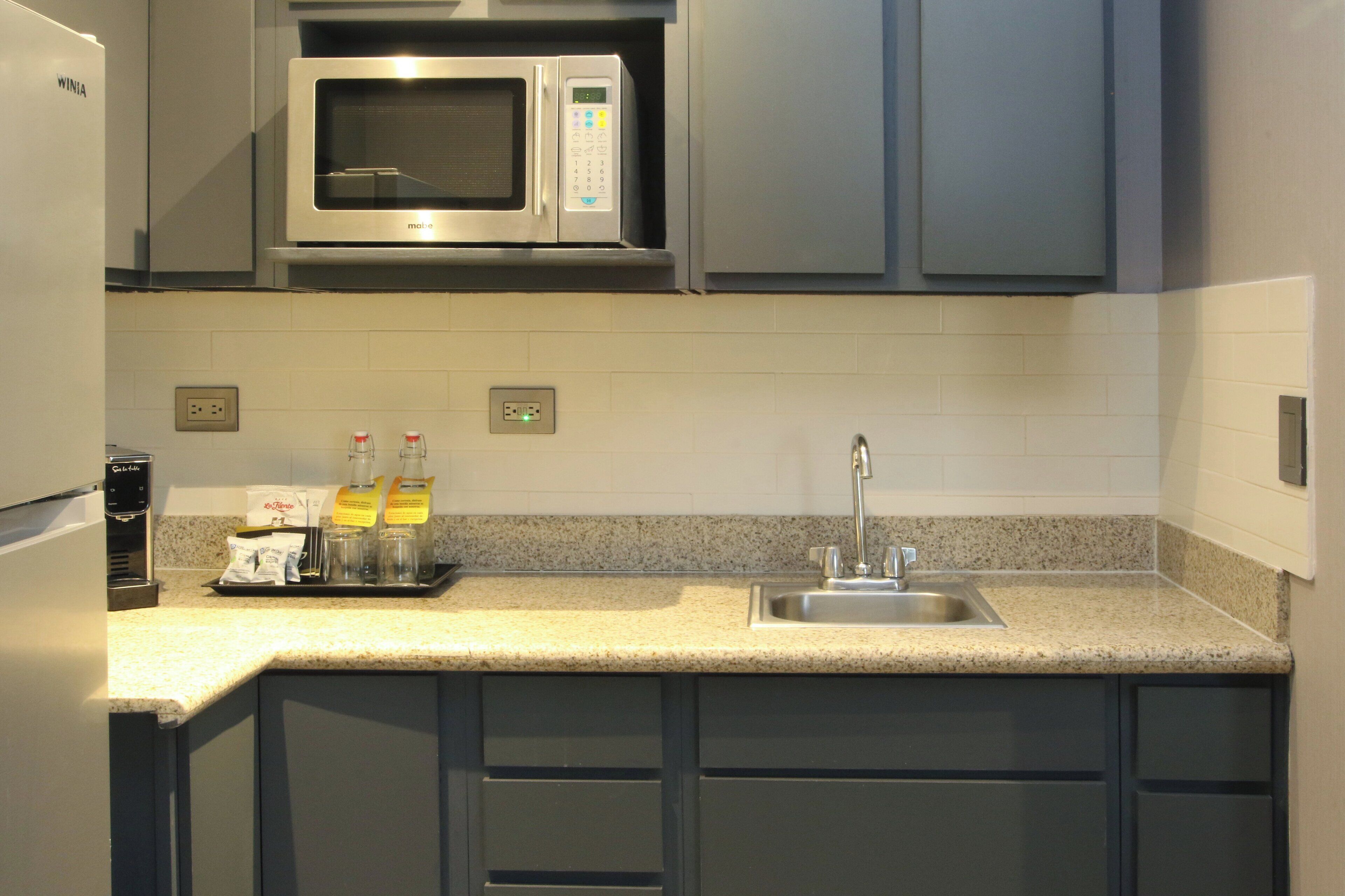 A modern kitchen with a built-in microwave, stainless steel sink, and granite countertop.