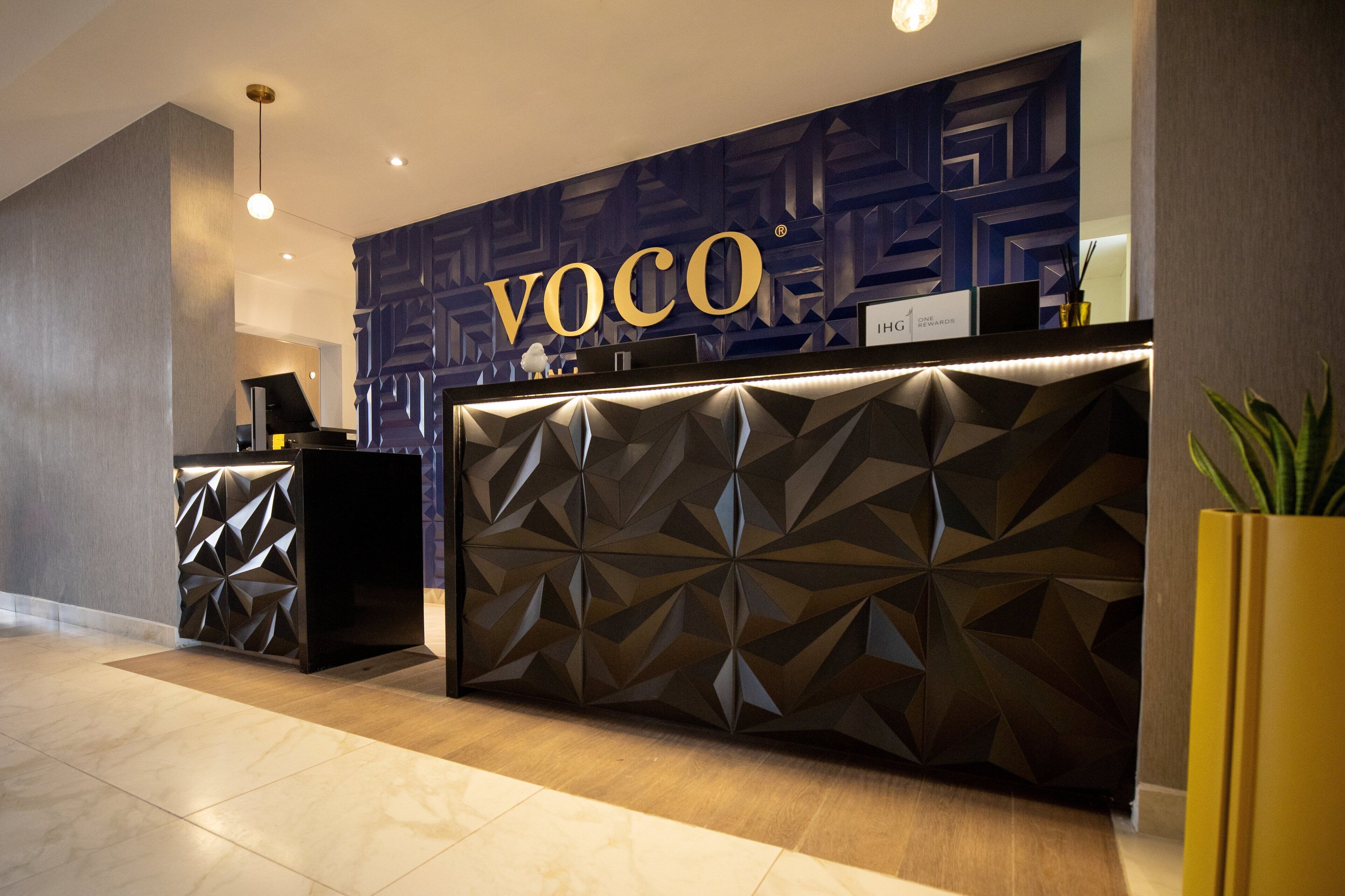 A reception desk with a geometric pattern and the name "VOCO" prominently displayed.