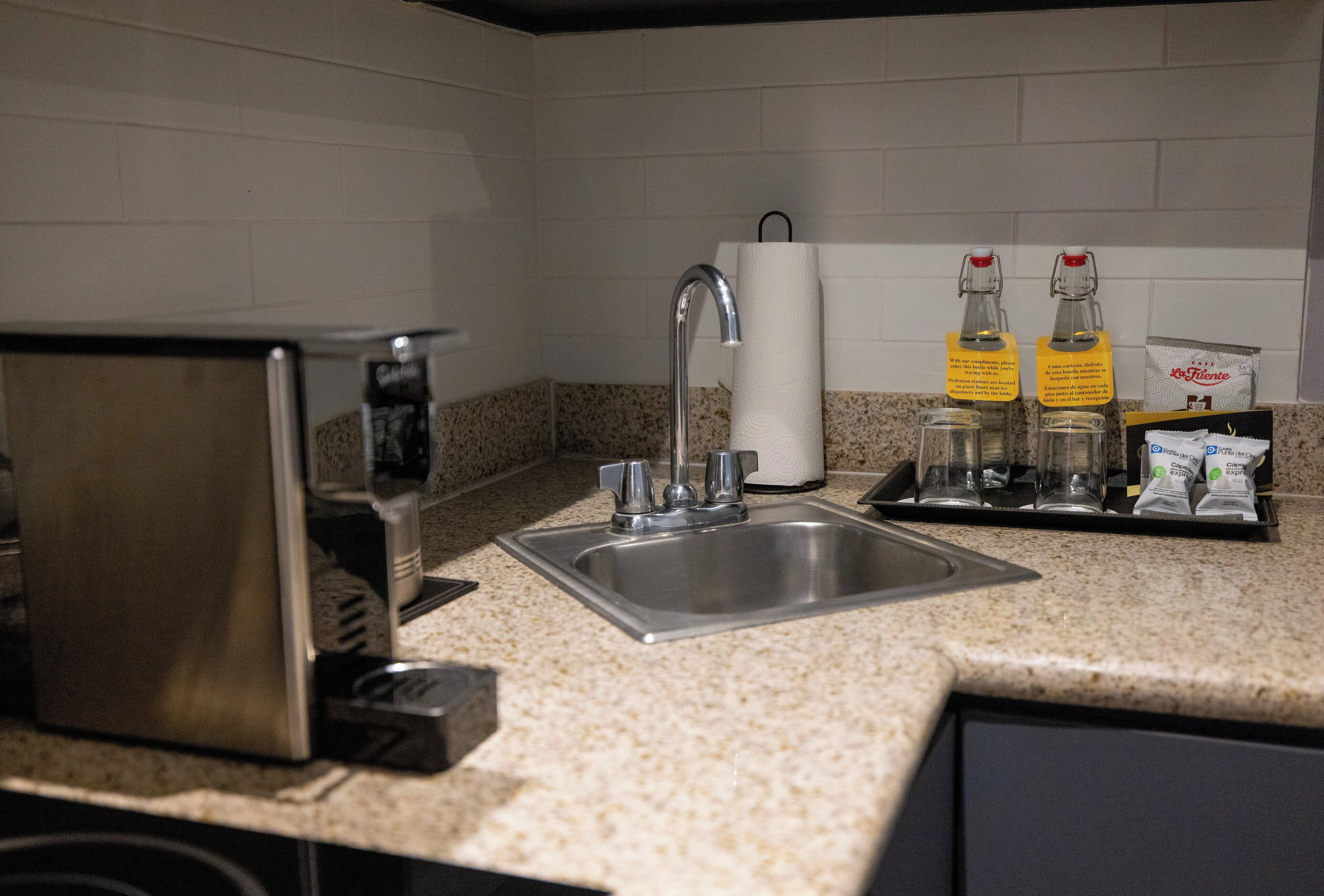 A kitchen with a stainless steel sink, a coffee maker, and two bottles of coffee creamer on the counter.