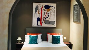 A hotel room with a large bed, two pillows, a nightstand with a lamp, and a painting on the wall. - Villa la Tour (Nice)