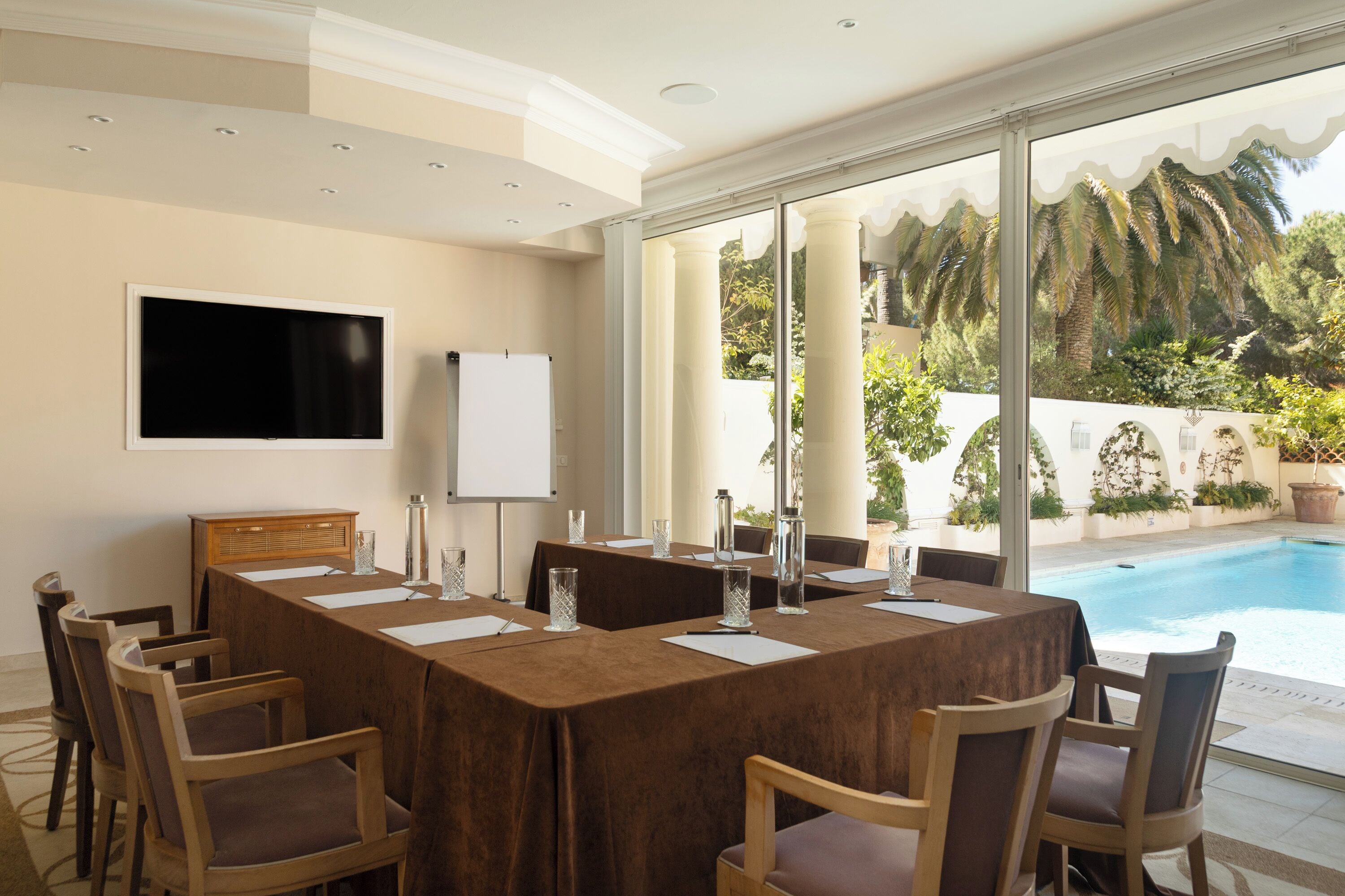 A conference room with a long table, chairs, a whiteboard, and a TV.