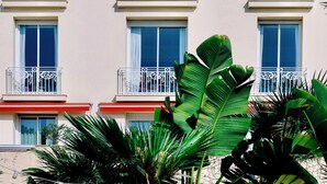 A building with balconies, a name 'JUANA' on the facade, and a person standing on one of the balconies. - Hotel Juana (Antibes)