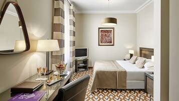 A hotel room with a bed, bedside table, TV, and a mirror.