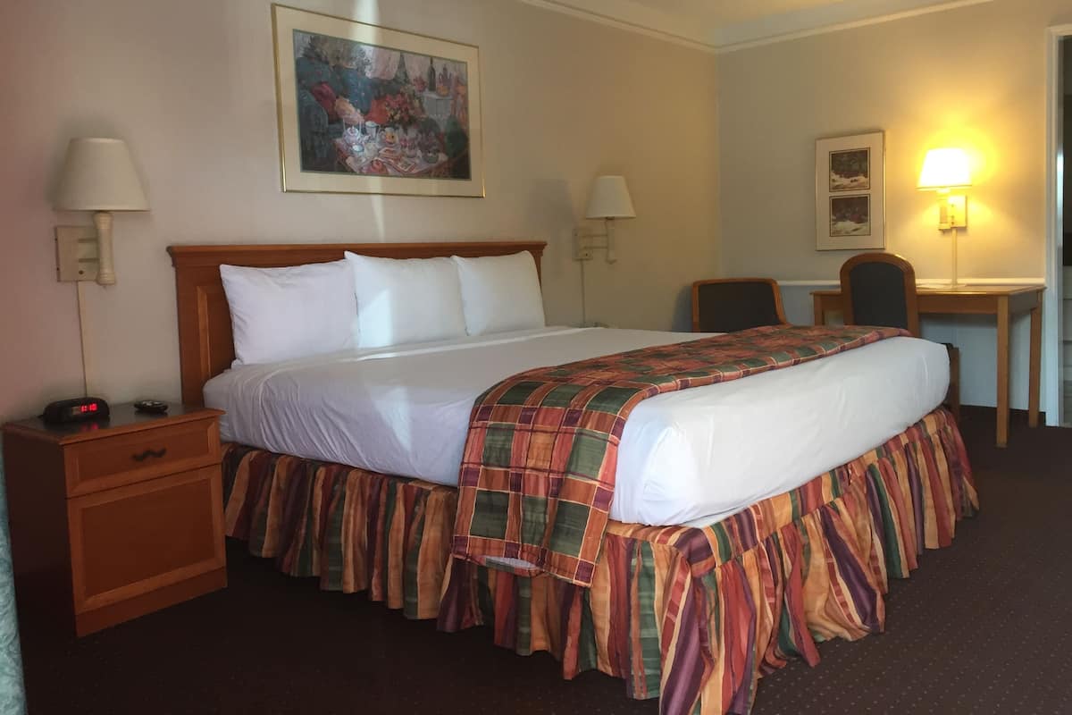 Ein Hotelzimmer mit Bett, Nachttischen, Schreibtisch und Stuhl.